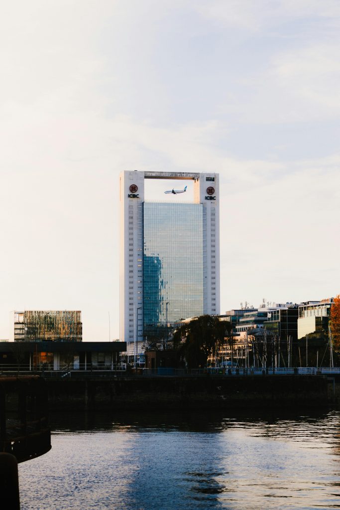 Airplane flies through a unique building frame in Buenos Aires skyline at sunset.